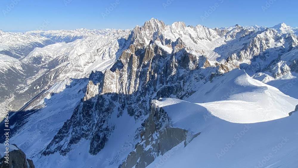 Naklejka premium High altitude winter alpine mountain landscape with snow covered peaks, glaciers and rugged ridges. Clean natural scenery suitable for travel, outdoor, environment and background use.