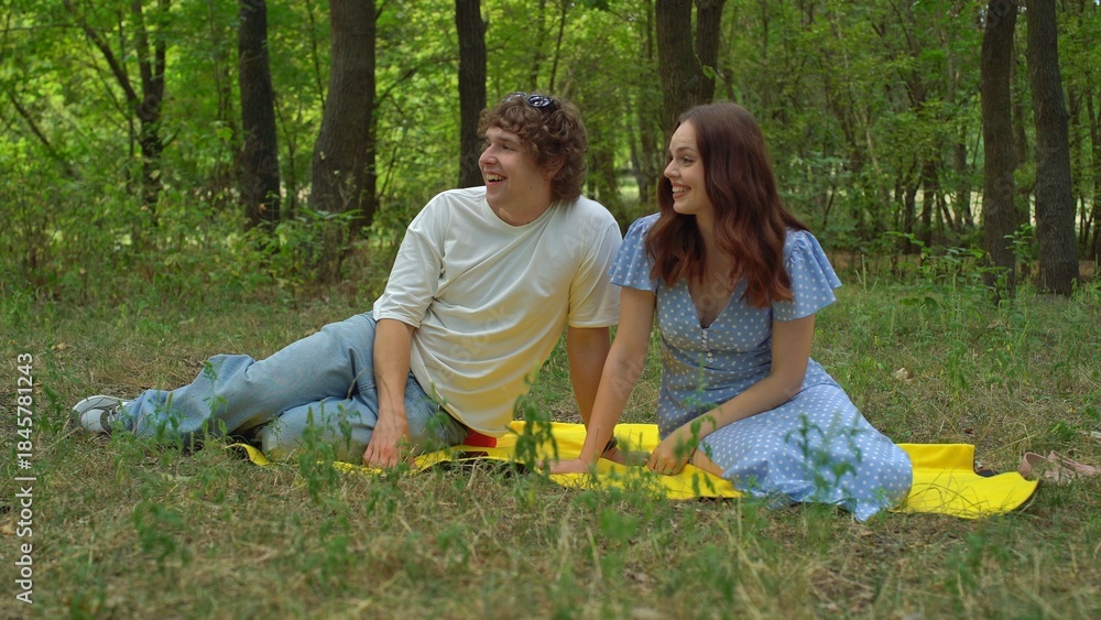 Fototapeta premium Smiling couple enjoying a summer picnic in the forest