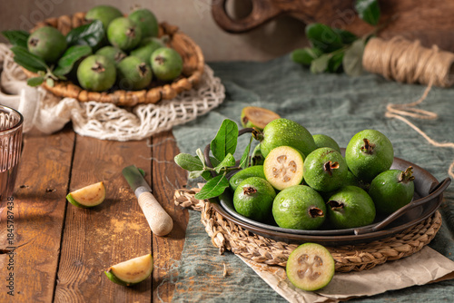 A rustic still life with ripe pineapple guavas, some cut open to reveal the fleshy pulp, on a small plate and in a basket