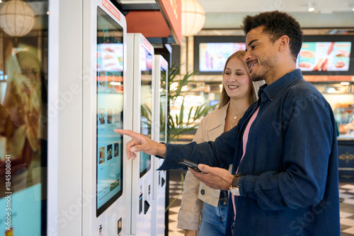 Couple using self service kiosk for fast food order