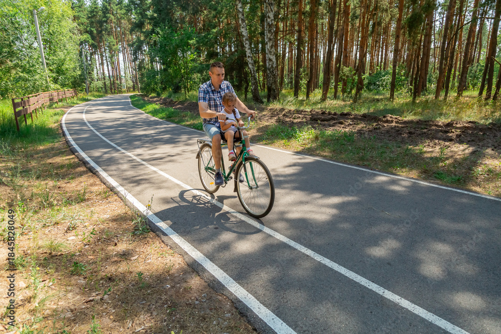 Fototapeta premium Young father with his little daughter on bicycle in summer sunny forest