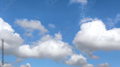Very light cumulus clouds move across the blue sky