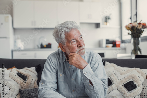 Konstfotografi Senior man sits alone on a sofa looking outside with a sad expression