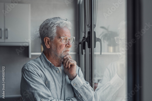 Fotografia Elderly man looks out the window with concern
