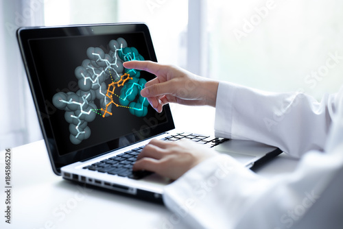 Closeup of researcher hand pointing at a laptop screen displaying 3D molecular model. Computational simulation shows protein drug interaction. Concept of biotechnology, medicine research.