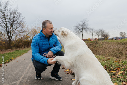 Man bonding with white swiss shepherd dog training outdoors