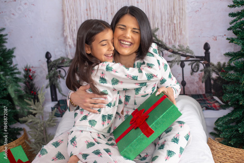 mom and daughter on a bed on Christmas morning giving a gift 
