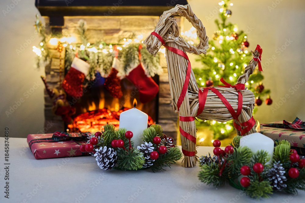 Fototapeta premium Julbock Christmas goat. A cozy Christmas setting with gifts, candles, a straw goat,