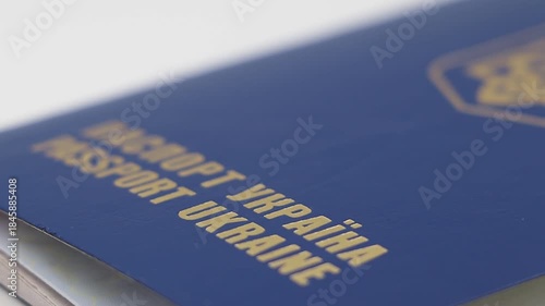 This close-up video showcases the intricate details of a blue Ukrainian passport cover as it rotates on a turntable. 