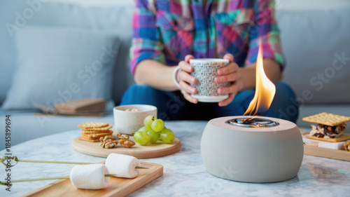 Portable tabletop fire pit with bioethanol flame on marble table, cozy indoor setup with snacks and hot drink, mini fire burner for home, small fireplace for balcony or living room ambiance
