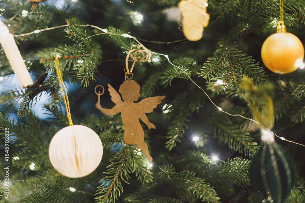 Obraz premium VIntage christmas angel toy hanging on xmas tree branch with festive lights. Happy New Year and Happy Holidays! ! Copy space. Stylish ornament