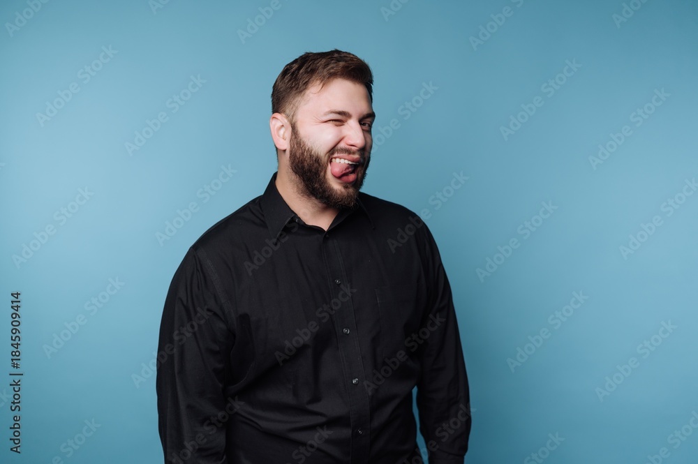Obraz premium Man shows expression while standing against a blue background in a studio setting during daytime