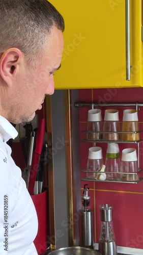Cheerful Man Cooking at yellow kitchen Communicating Over a Digital Tablet. Middle-aged Man using tablet in his kitchen and talks with the person, over the internet, about the cooking process.