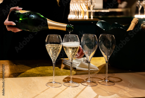 Pouring in glasses of french sparkling wine champagne with little bubbles, tasting wine, celebration, wedding or champagne tour with visit of caves, Reims, France