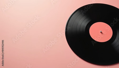 Black vinyl record with pink center label rests on soft pink backdrop. This classic retro music object evokes nostalgia and offers clean design for creative use. It highlights vintage sound aesthetic.