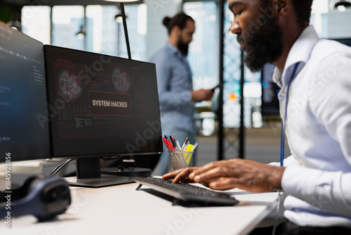 Close up of software developer blocking network intrusion inside office. IT professional responding to live cyberattack alert, neutralizing hacker breach in tech startup workspace