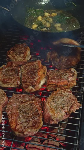 close-up footage of grilling steaks, barbecue party in evening, the meat is stewed in butter with garlic and thyme, spiking pieces of meat on the grill, various vegetables, lots of smoke