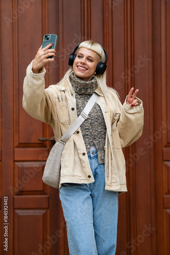 Canvas-taulu Young woman taking selfie with headphones smiling