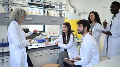 Senior female professor lecturing diverse science students in a university laboratory