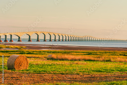 Hay harvesting and iconic Confederation bridge linking the provinces of New Brunswick and Prince Edward island, Atlantic coast of Canada