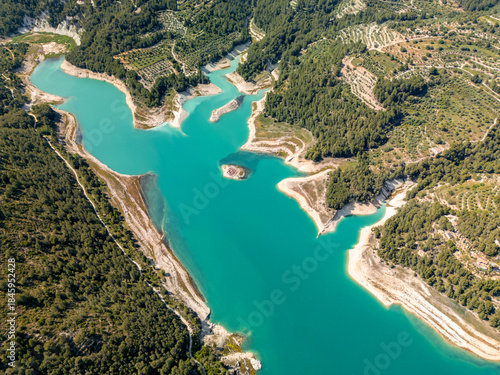 Stunning aerial photo of a turquoise reservoir surrounded by lush forest and terraced hills in South Spain, perfect for travel, nature, and landscape inspiration.