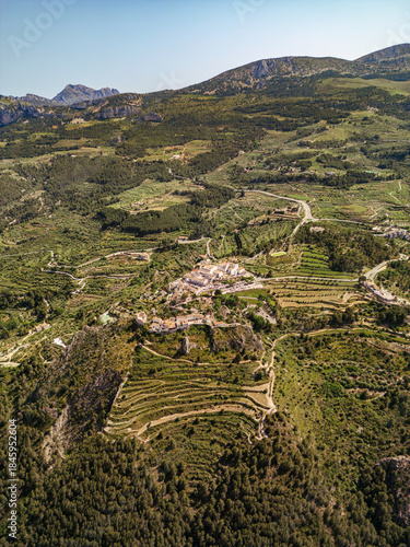 Drone photo of a rural village surrounded by terraced fields and lush mountains in South Spain, ideal for travel, agriculture, and landscape inspiration or editorial use.