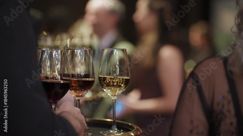 Waiter Carrying Tray Of Red And White Wine Glasses Through Crowded Reception, Guest Hand Reaching For Glass, Bustling Elegant Event Service