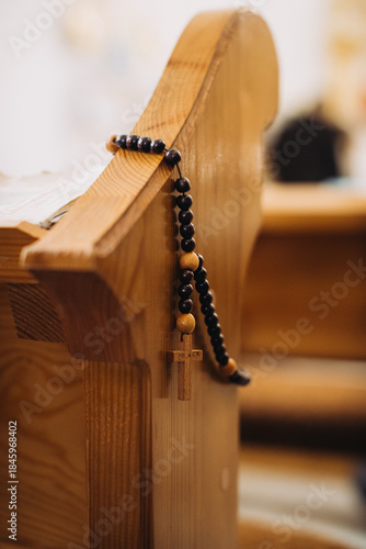 Rosary hanging on wooden church pew during baptism