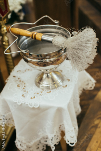 Holy water font and aspergil during christian baptism ceremony