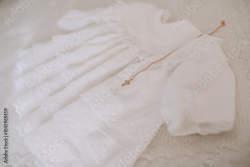 White baptismal gown with gold cross necklace