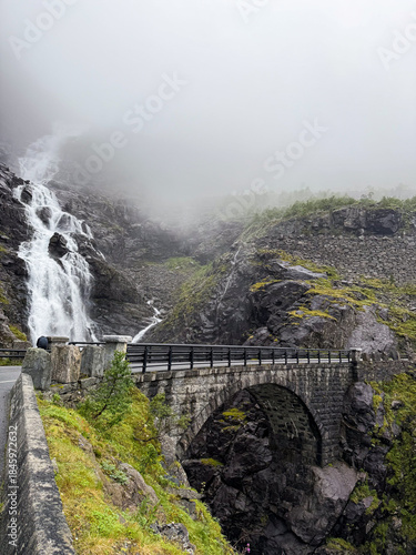 Trollstigen road winding through foggy mountain waterfalls