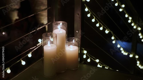 Candles On Railing With String Lights, Tall Glass Votives, Warm Flame, Deep Shadows, Dramatic Contrast, Moody Bokeh, Empty Rooftop Corridor,