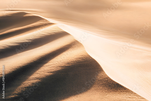 Sand dunes under soft sunlight at golden hour showcasing natural patterns and textures