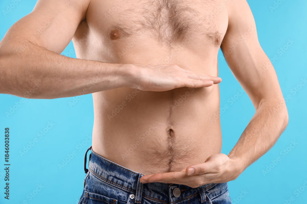Naklejka premium Man with healthy stomach on light blue background, closeup