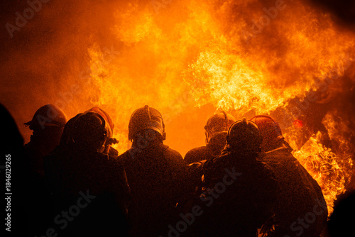Silhouette of firefighters training for disaster relief officers.Firefighter using water and fire extinguishers to fight the flames in emergency situations in a dangerous area fire site on night time