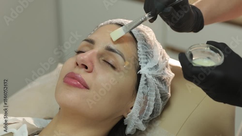 Cosmetologist applying chemical peel on woman's face