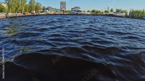 Wallpaper Mural Low-angle view of rippling water near Andrejosta in Riga, catching sunlight, harbor details, yachts, and industrial silhouettes in a bright coastal atmosphere. Torontodigital.ca