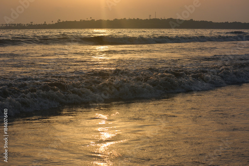 Golden sunset over gentle ocean waves at serene tropical beach