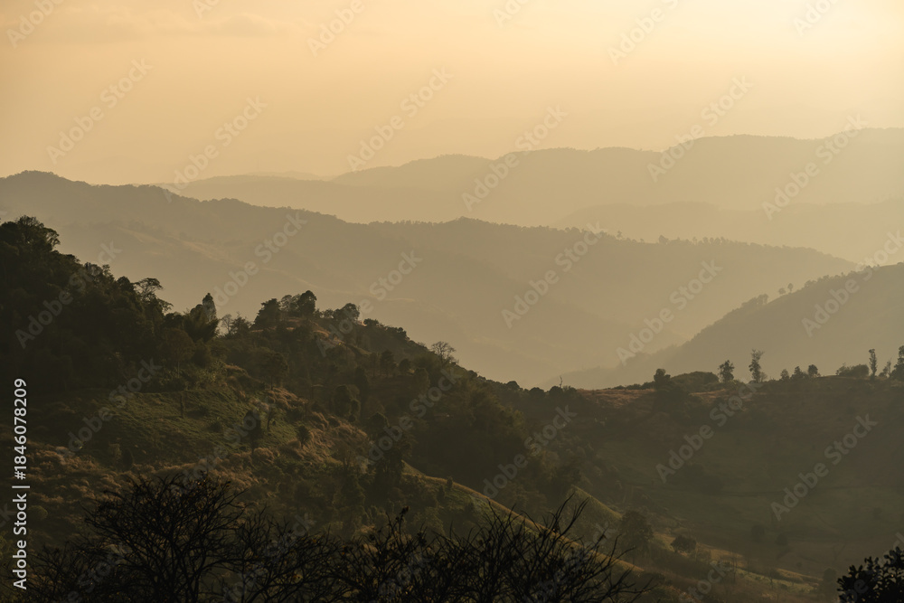 Obraz premium Serene Sunrise Over Rolling Mountains with Layers of Fog and Soft Light Casting Shadows Across the Landscape in a Tranquil Environment