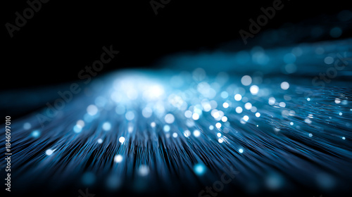 Close-up of glowing blue fiber optic cables creating a futuristic, high-speed data transmission effect with bright light points against a dark background
