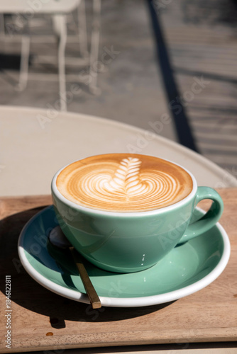 Hot latte coffee with beautiful latte art serve in green color cup