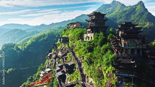 Aerial shot of traditional chinese wooden pavilions and cliffside houses on green mountain. The famous Wangxiang Valley Scenic Area is located in Jiangxi, China.
