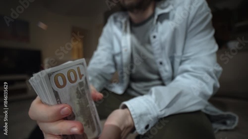 Man holding thick stack of dollar bills flipping cash toward camera. Money fanning and thumbing gesture for wealth profit income hustle success