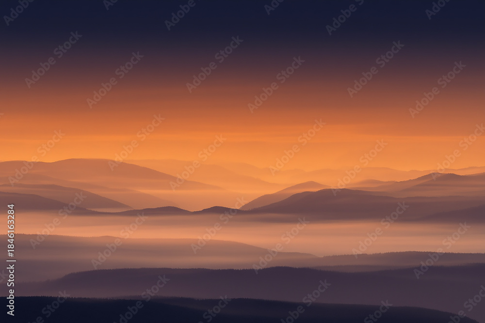 Obraz premium Vibrant sunset over misty mountain landscape with warm orange sky