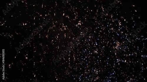 Golden fireworks burst brilliantly across a dark night sky, illuminating the celebration