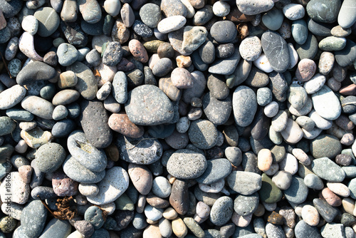On a serene day, discover a spa retreat nestled by the blue sea. The beach is lined with smooth, colorful pebbles, inviting relaxation and rejuvenation in a luxurious setting.
