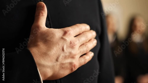 Hand over heart, group of people in background, pledge