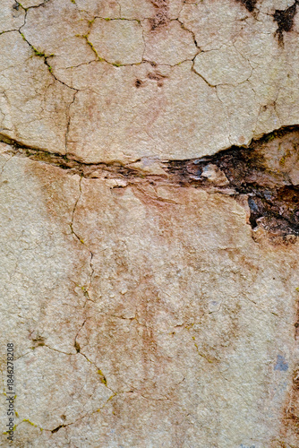 Close-up of natural stone surface texture with cracks and weathered details. Abstract rocky background showing aged mineral patterns and rough stone structure.