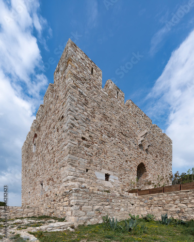 Historic Guvercinada Kalesi, or Kucckada, stone fortress walls under blue sky with white clouds, Kusadasi, Turkey. Low angle view