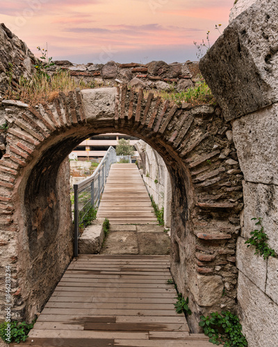 Ancient Roman archway with a wooden walkway at the Agora of Smyrna archaeological site at sunset. Izmir, Turkey